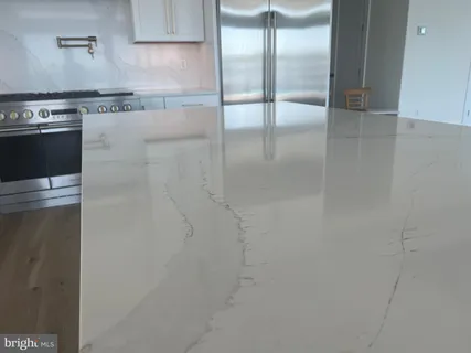 a kitchen with stainless steel appliances granite countertop a sink a stove a refrigerator and island with wooden floor