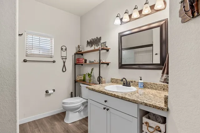 a bathroom with a granite countertop toilet sink mirror and vanity