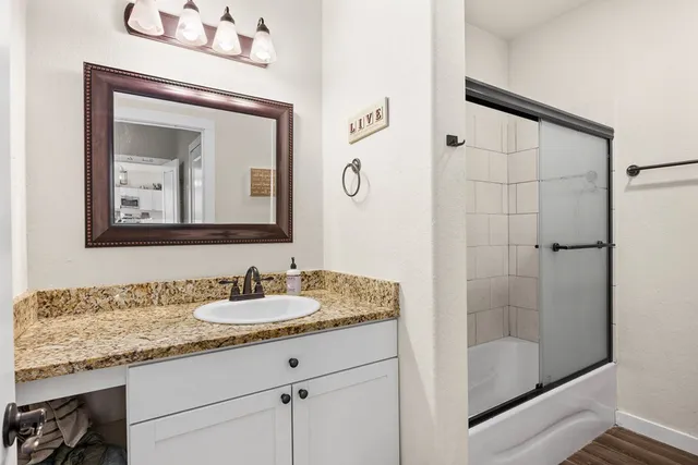 a bathroom with a granite countertop sink a mirror and shower