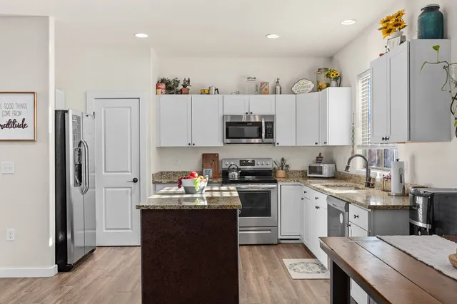 a kitchen with stainless steel appliances a sink a stove a refrigerator cabinets and a window