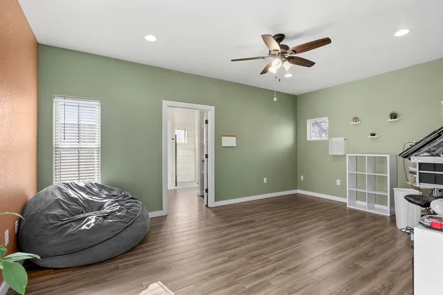 a living room with hard wood flooring and a ceiling fan