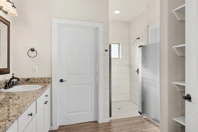 a spacious bathroom with a granite countertop sink a mirror and shower
