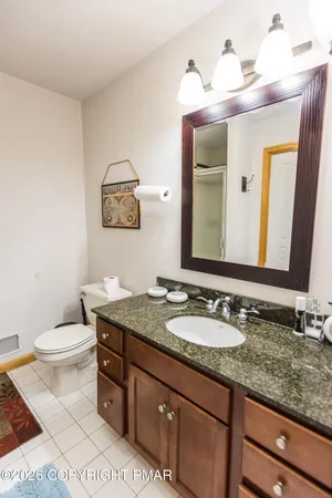 a bathroom with a granite countertop toilet sink and mirror
