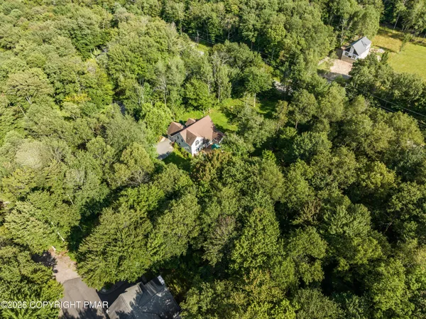 an aerial view of residential house with outdoor space and trees all around