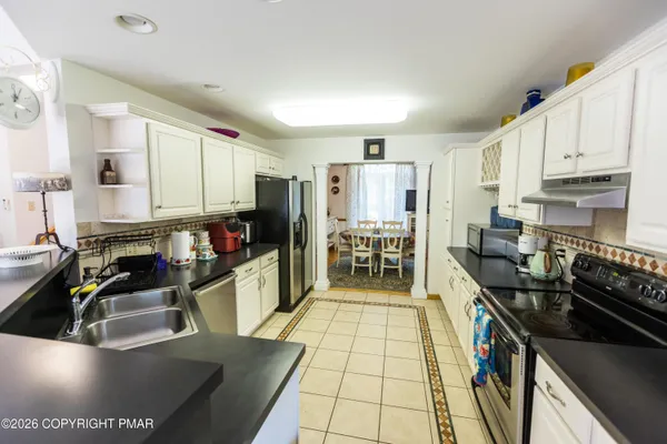 a kitchen with stainless steel appliances granite countertop a stove top oven a sink a dining table and chairs with wooden floor