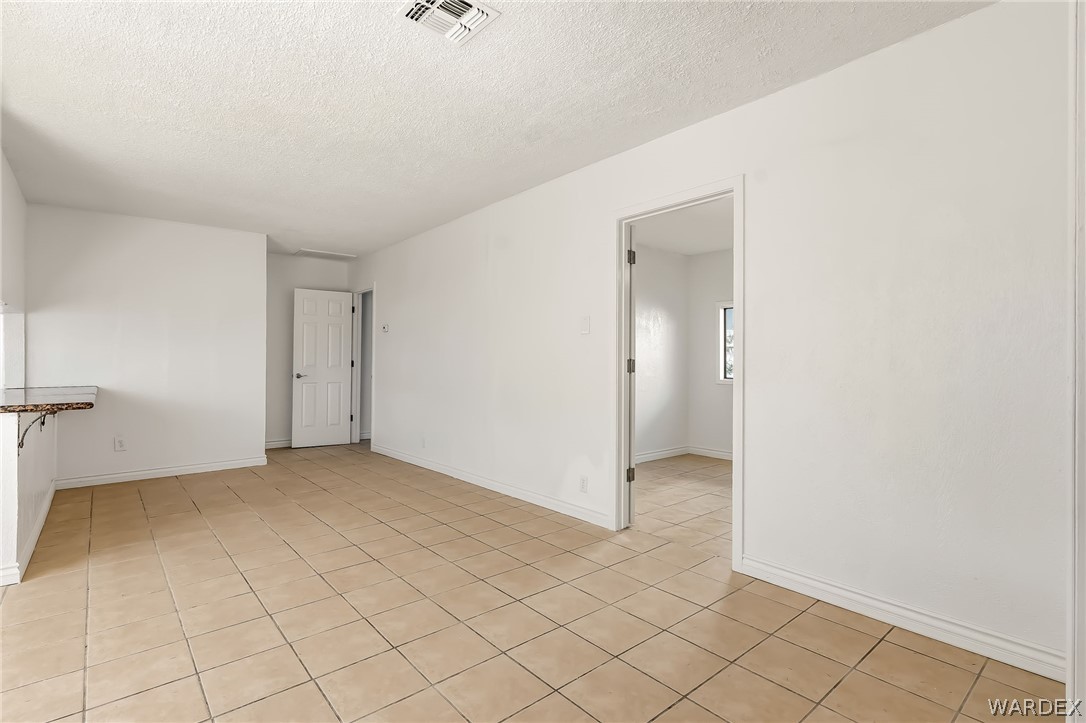 1628 Ramar Road Bullhead City, AZ 86442 - Photo 41 of 64 Spacious room featuring tile flooring, white walls, and a light-colored ceiling