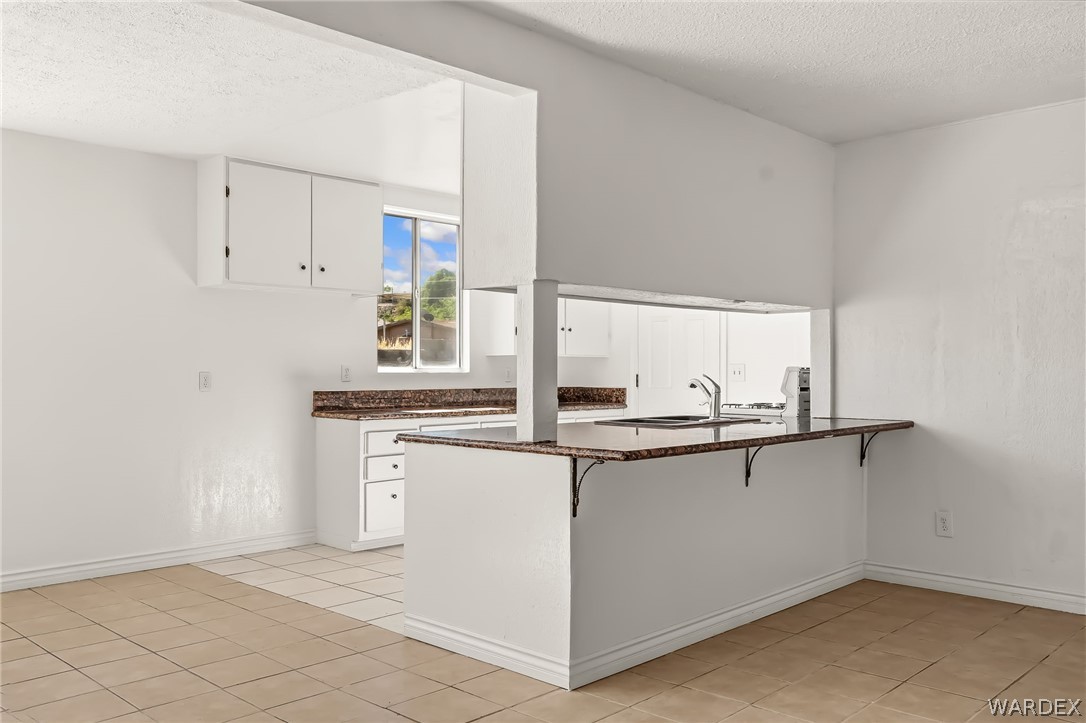 1628 Ramar Road Bullhead City, AZ 86442 - Photo 47 of 64 The kitchen features a breakfast bar, white cabinetry, and granite countertops