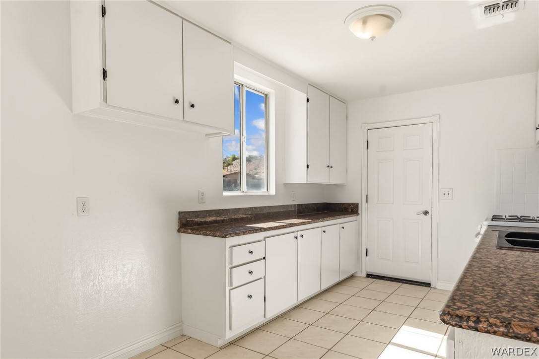 1628 Ramar Road Bullhead City, AZ 86442 - Photo 51 of 64 This kitchen features white cabinetry, granite countertops, and tiled flooring