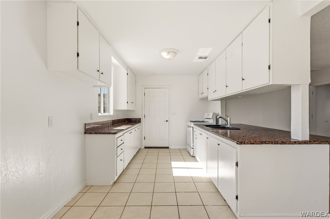 1628 Ramar Road Bullhead City, AZ 86442 - Photo 52 of 64 The kitchen features extensive white cabinetry, granite countertops, and tiled flooring