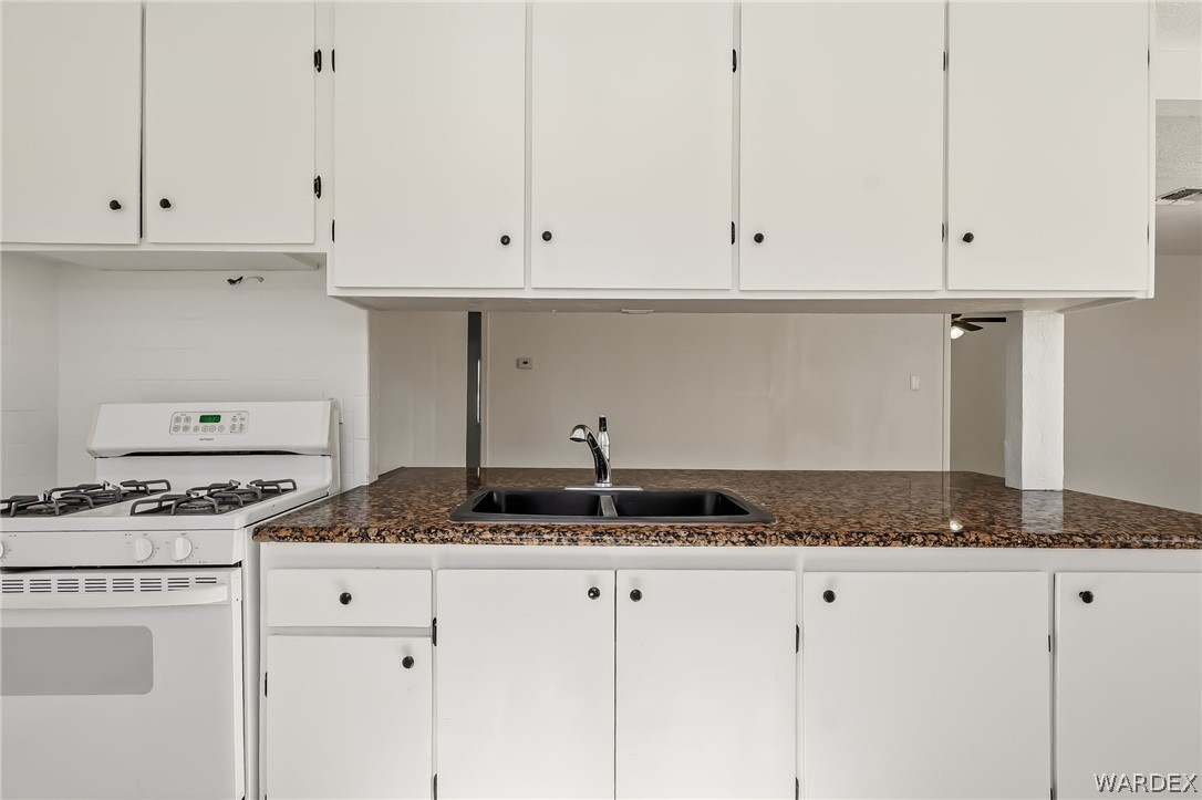 1628 Ramar Road Bullhead City, AZ 86442 - Photo 53 of 64 Kitchen featuring white cabinetry, a black sink with a chrome faucet, and granite countertops