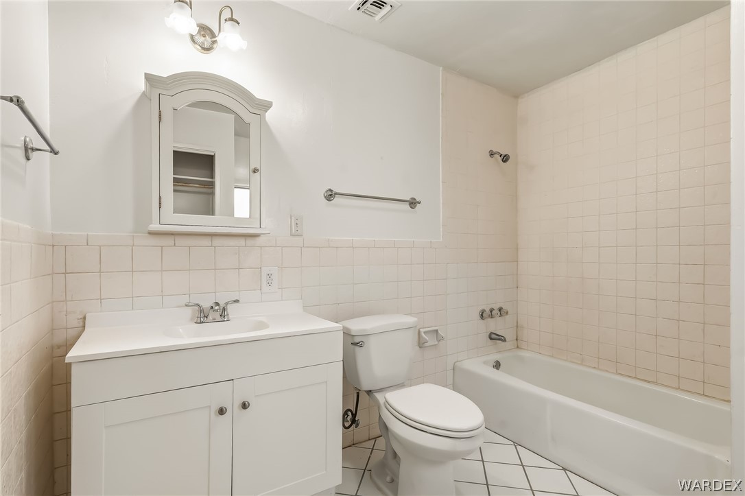 1628 Ramar Road Bullhead City, AZ 86442 - Photo 59 of 64 Primary bathroom features a white vanity with storage, a cast iron bathtub, and white tiled walls