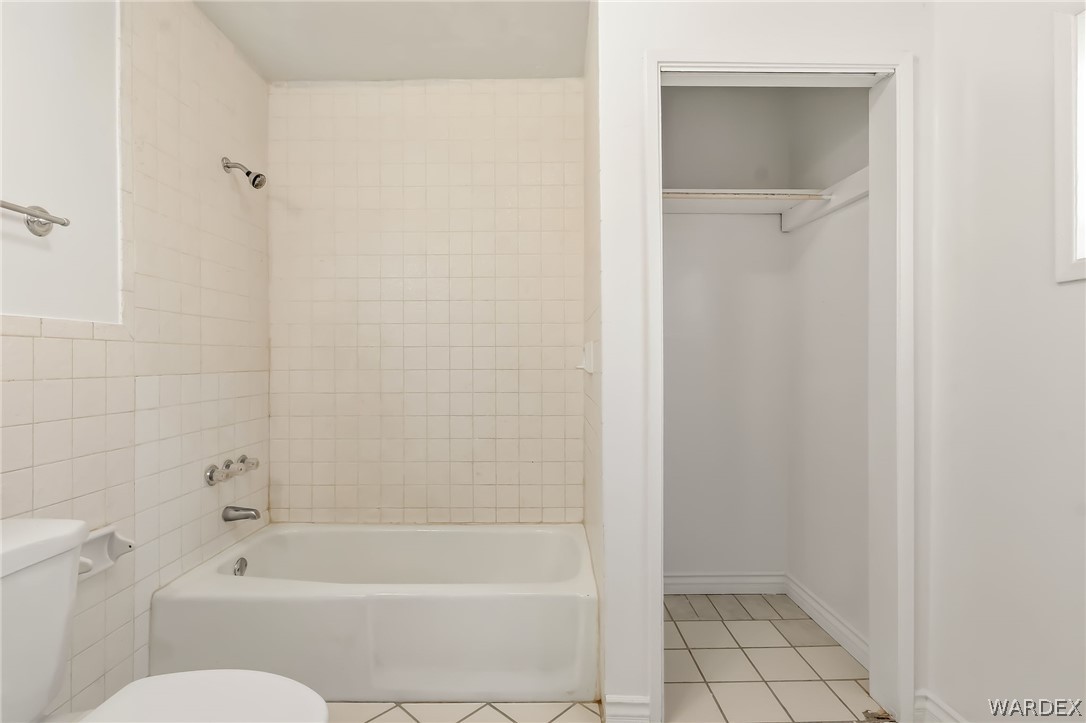 1628 Ramar Road Bullhead City, AZ 86442 - Photo 60 of 64 The bathroom features a bathtub with a shower, ceramic wall tiles, and an adjacent storage area with tiled flooring