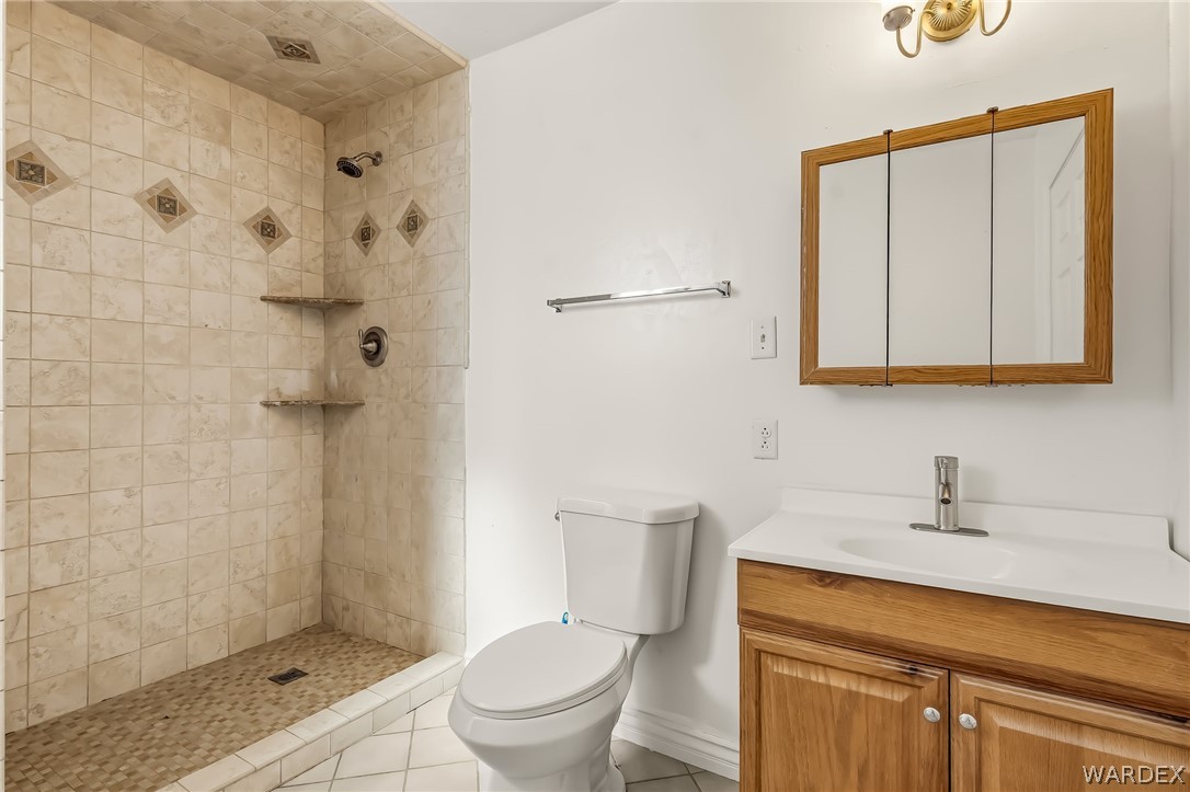 1628 Ramar Road Bullhead City, AZ 86442 - Photo 62 of 64 Guest bathroom with a tiled walk-in shower featuring built-in shelves and a pebble-style floor