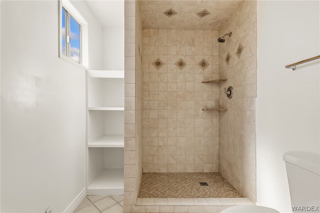 1628 Ramar Road Bullhead City, AZ 86442 - Photo 63 of 64 Guest bathroom features a tiled walk-in shower with decorative accents, a shower head, and built-in shelving