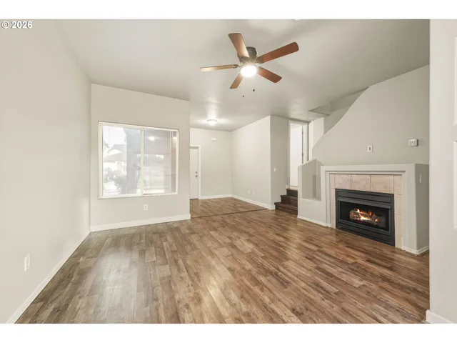a view of empty room with wooden floor fireplace and a window