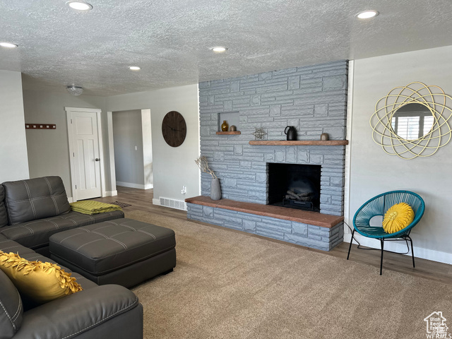 702 North 100 West Logan, UT 84321 - Photo 14 of 58 Living room with a stone fireplace, a textured ceiling, baseboards, and visible vents