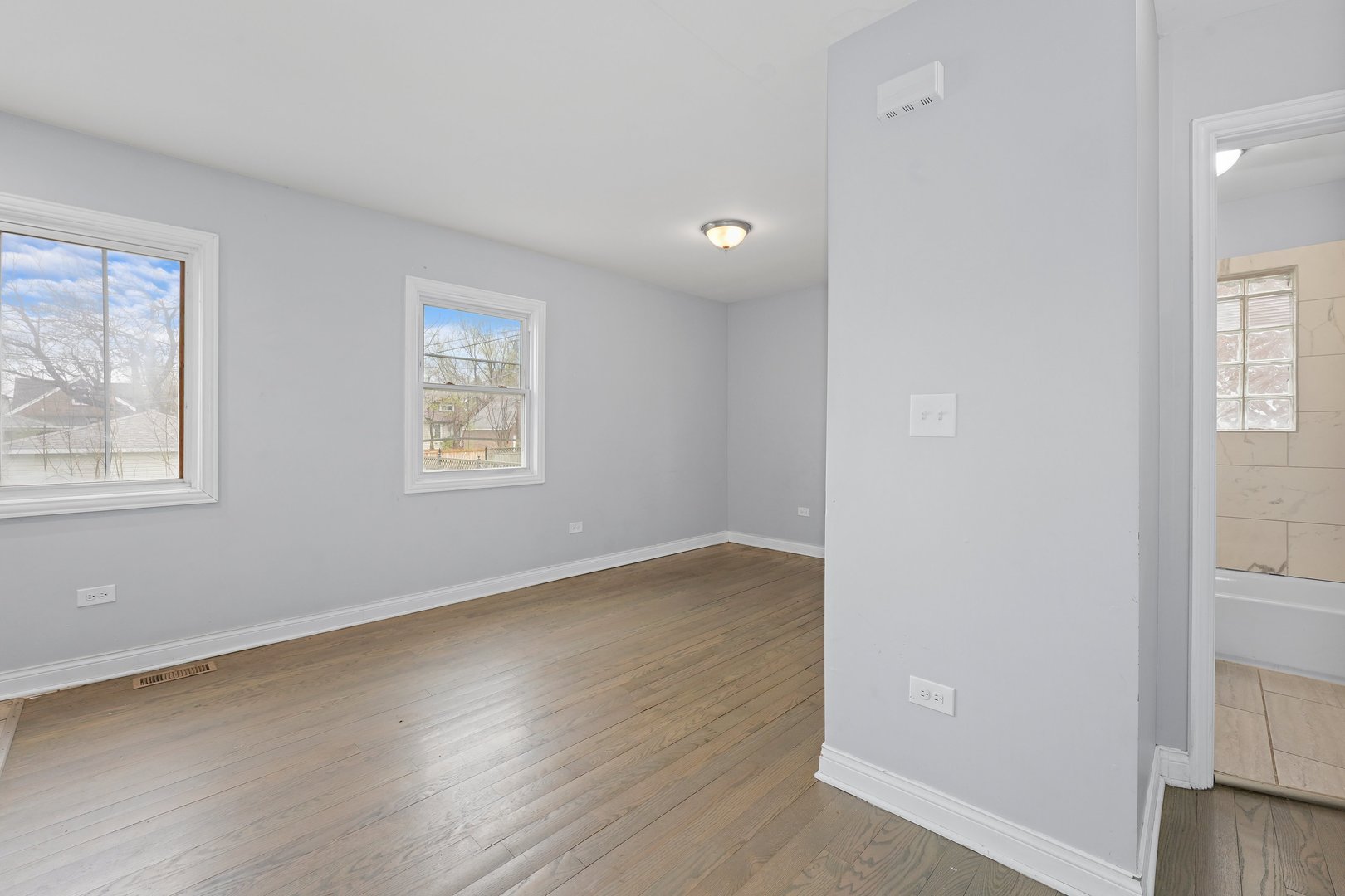 10233 South Calhoun Avenue Chicago, IL 60617 - Photo 8 of 22 an empty room with wooden floor and windows