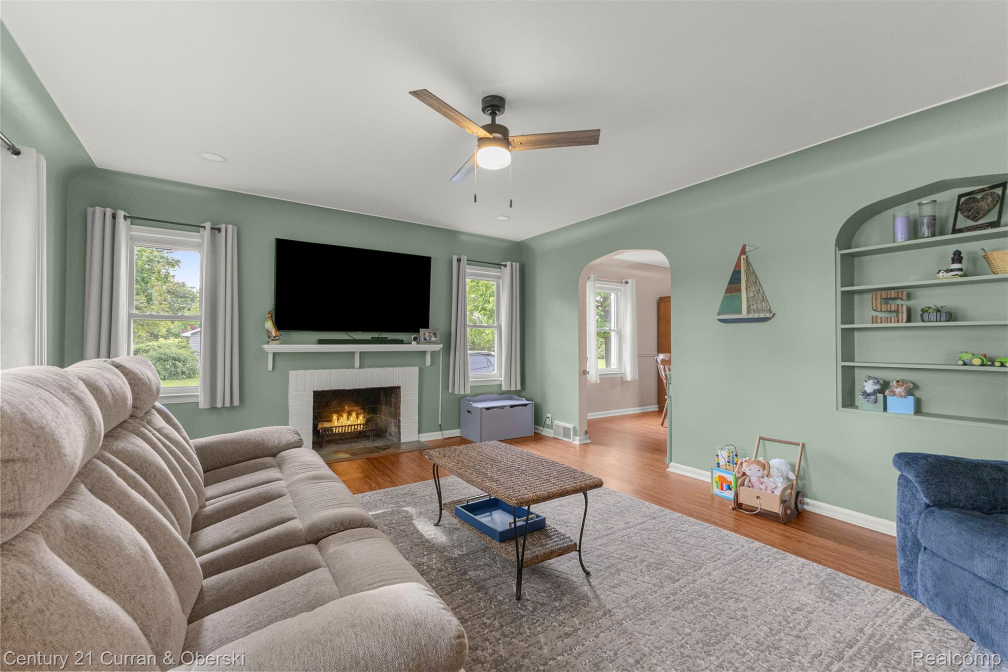 411 South Adrian Street Tecumseh, MI 49286 - Photo 7 of 61 Living room featuring wood finished floors, ceiling fan, arched walkways, built in features, and a fireplace