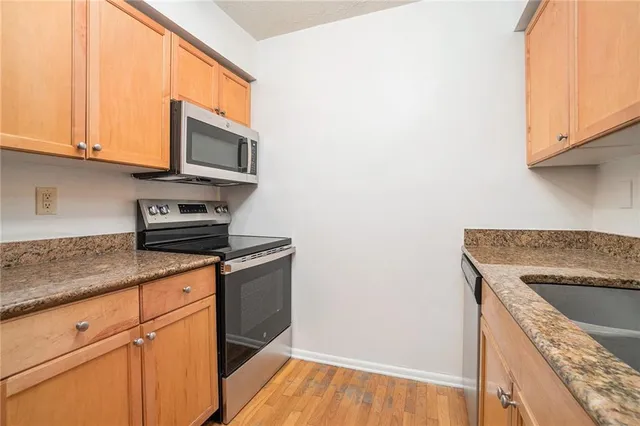 a kitchen with granite countertop wooden cabinets a sink and dishwasher