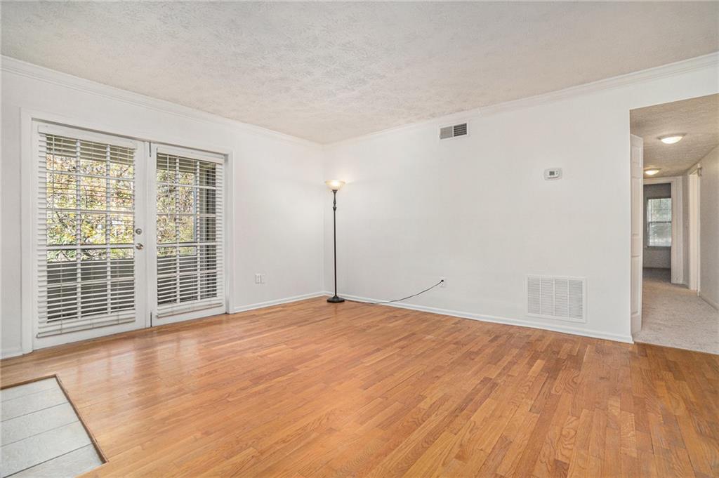 1150 Collier Road Northwest, Unit 12F Atlanta, GA 30318 - Photo 3 of 26 a view of an empty room with wooden floor and a window