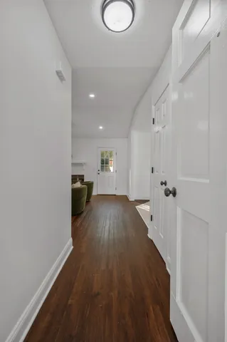 a view of a hallway with wooden floor and a bathroom