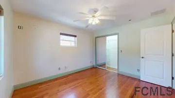 an empty room with wooden floor and fan
