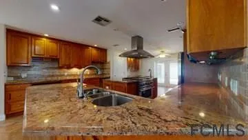a kitchen with stainless steel appliances granite countertop a sink a stove and a wooden cabinets