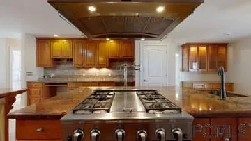 a kitchen with kitchen island granite countertop a stove and a sink