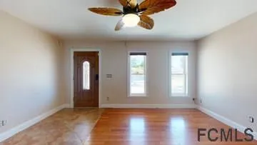 a view of an empty room with window and wooden floor