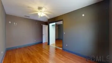 a view of an empty room with chandelier fan and a window