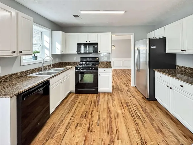 a large kitchen with stainless steel appliances granite countertop a stove a sink and a refrigerator