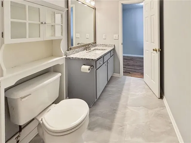 a bathroom with a granite countertop toilet sink and mirror