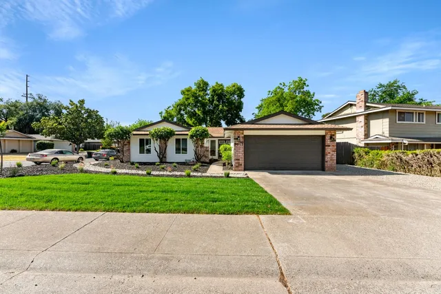 a front view of a house with a garden and trees