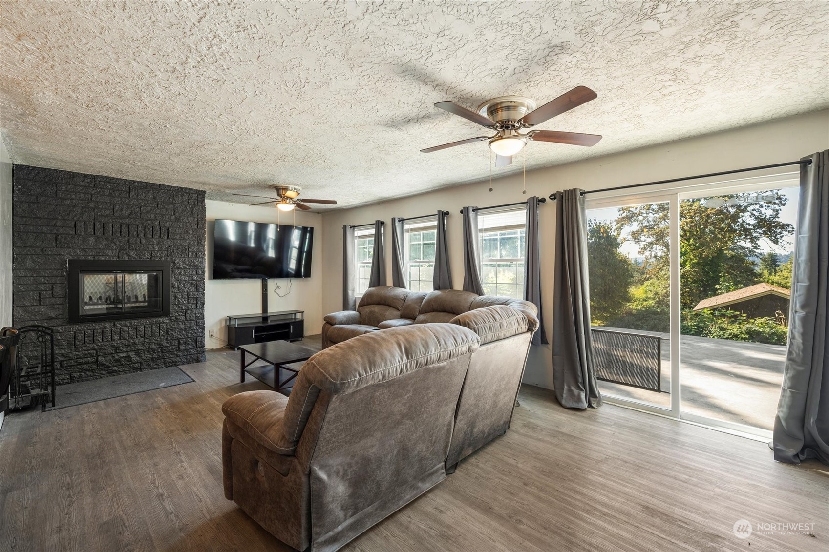 3827 Sunset Way Longview, WA 98632 - Photo 13 of 40 a living room with furniture a flat screen tv and floor to ceiling windows