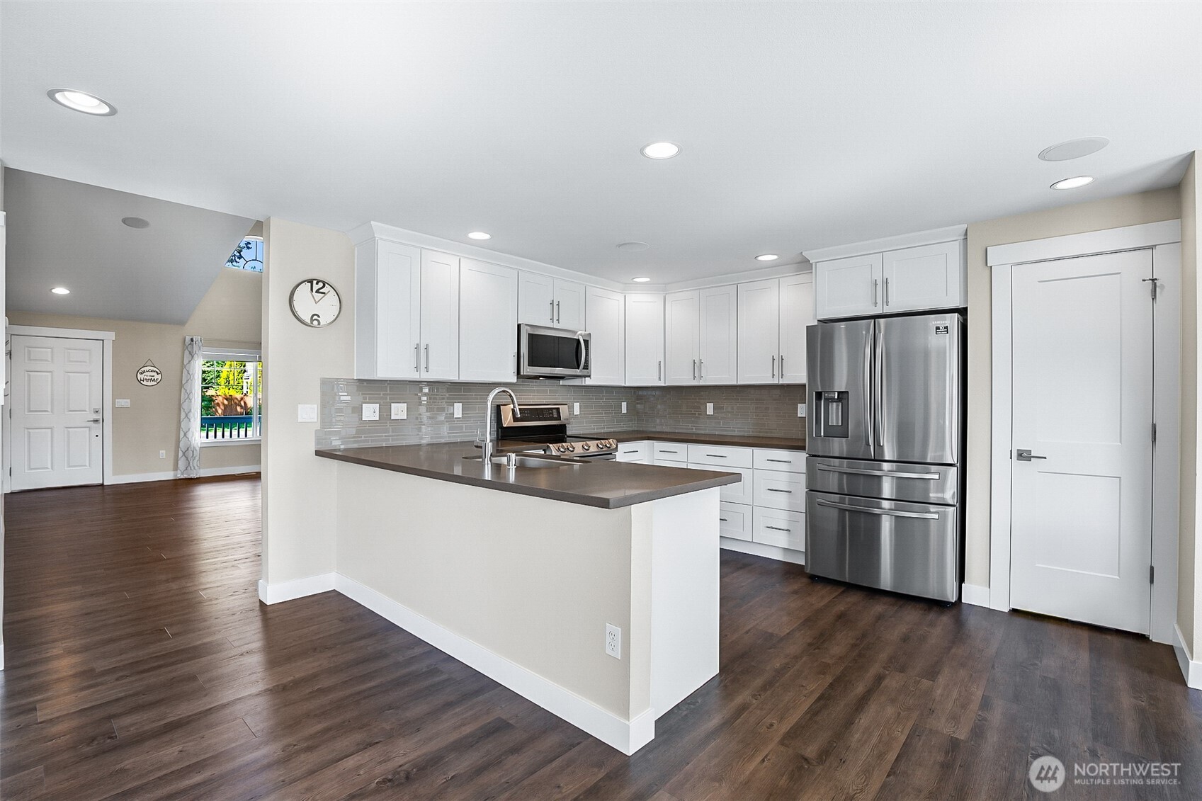 708 Rosario Place Northeast Renton, WA 98059 - Photo 7 of 38 a kitchen with stainless steel appliances granite countertop a refrigerator a stove top oven a sink and white cabinets with wooden floor next to windows