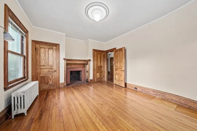an empty room with wooden floor fireplace and windows