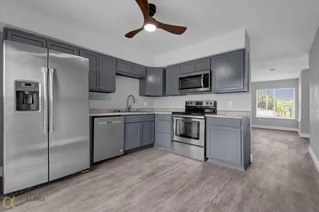 a kitchen with granite countertop a refrigerator stove top oven and sink