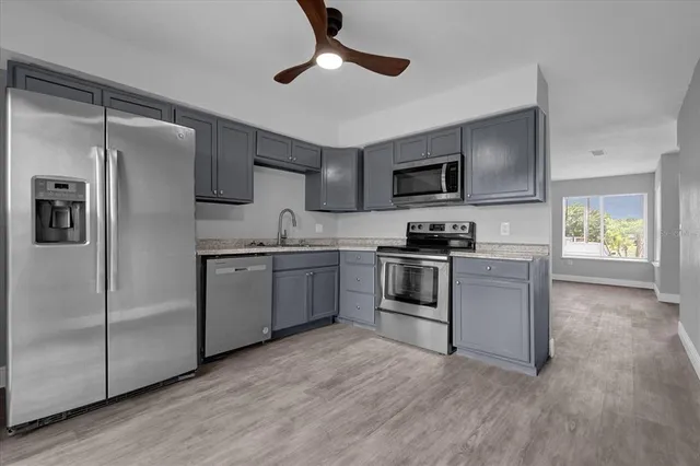 a kitchen with granite countertop a refrigerator stove top oven and sink