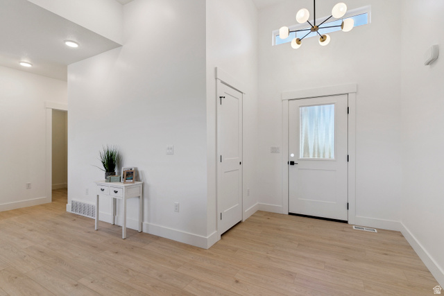 5777 West 4100 South Hooper, UT 84315 - Photo 2 of 41 Foyer entrance with a chandelier, light wood-style floors, and a high ceiling