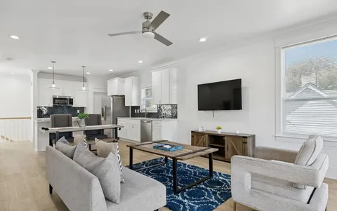 a living room with furniture kitchen view and a flat screen tv