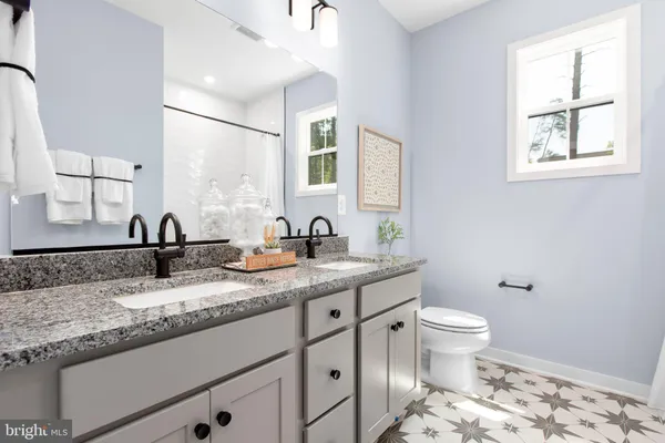 a bathroom with a granite countertop sink and a toilet