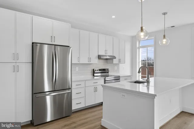 a kitchen with stainless steel appliances a refrigerator sink and wooden floor