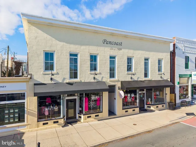 a view of large building with a lot of people on the roadside