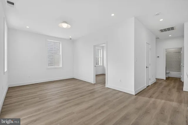 an empty room with wooden floor & windows