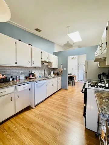 a large kitchen with cabinets wooden floor and stainless steel appliances