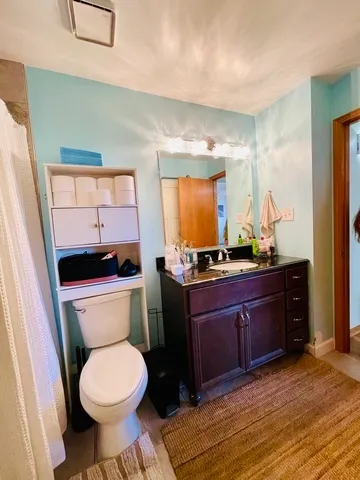 a bathroom with a granite countertop toilet sink and mirror