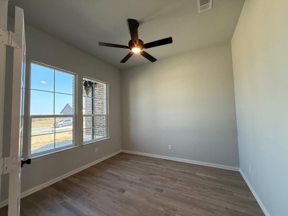 409 Hayden Faith Court Springtown, TX 76082 - Photo 7 of 23 an empty room with wooden floor fan and windows