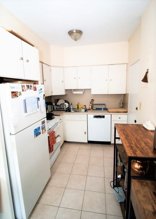 116 Sutherland Road, Unit 11 Boston, MA 02135 - Photo 2 of 6 a kitchen with a stove a sink and white cabinets