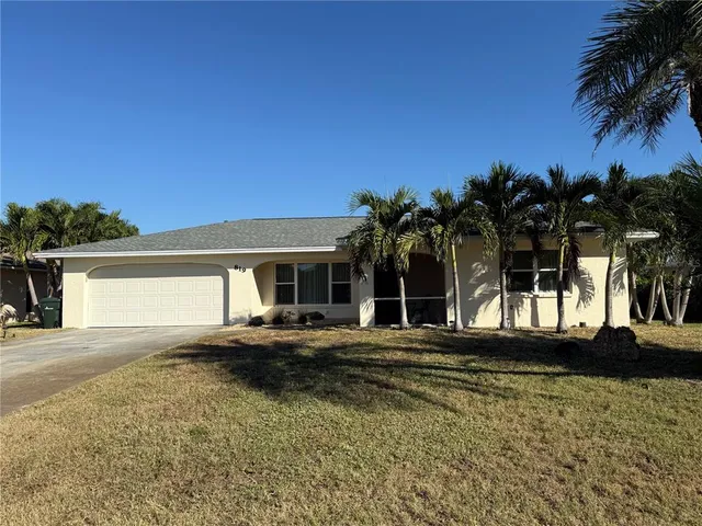 front view of house with a yard and palm trees