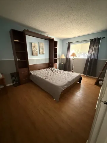 a bedroom with a bed table chair and window